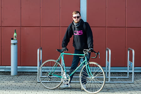 Person In Black Hoodie Holding Green Bike thumbnail