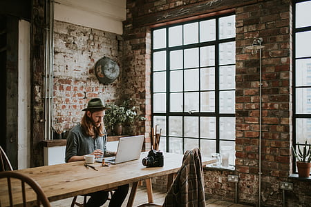 man uses laptop on brown wooden tble thumbnail