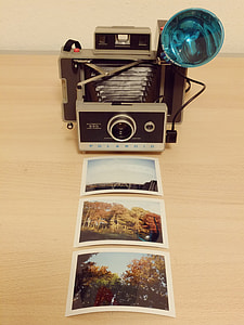 grey folding camera in front of three photographs thumbnail