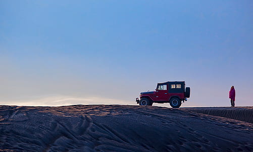 red and black vehicle with person standing on desert thumbnail
