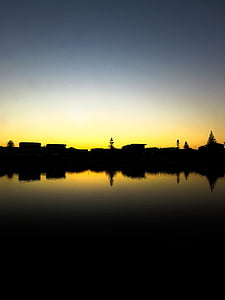 silhouette of houses and trees near body of water thumbnail