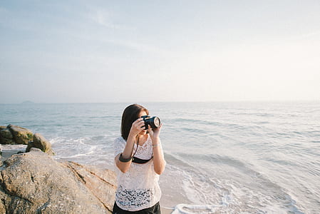 woman taking photo near sea thumbnail
