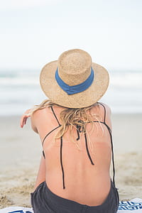 woman sitting on the beach wearing brown knit hat thumbnail