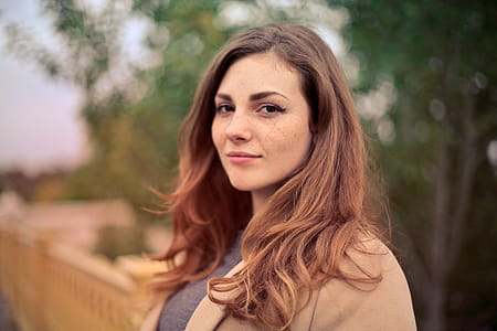 Brown Haired Young Woman In Camel Jacket Looking At Camera thumbnail