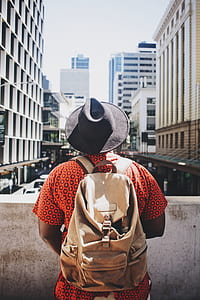 man wearing backpack and facing the high rise building thumbnail