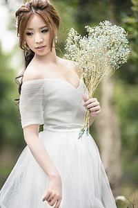 woman wearing white off-shoulder wedding dress holding white petal flower thumbnail