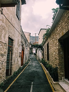 Black Road in Between Beige Walls Under Cloudy Sky thumbnail