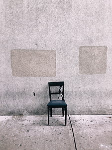 black wooden armless chair in front of gray wall thumbnail