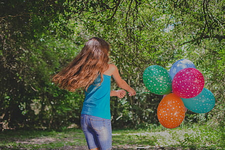 girl playing near trees holding balloons thumbnail
