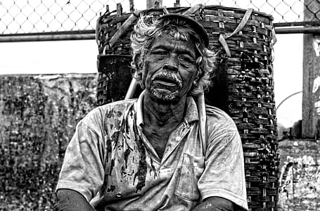 Man in Polo Shirt Sitting Near Brown Woven Basket Black and White Photography thumbnail