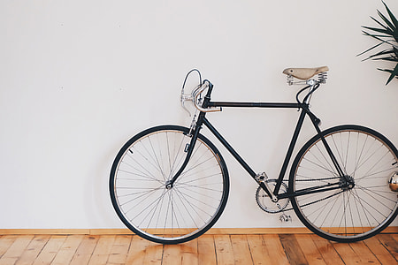 black city bike leaning on white painted wall thumbnail