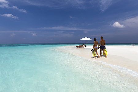man and woman walking on white sand during daytime thumbnail