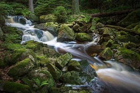 river between green grass-covered rocks during daytime thumbnail