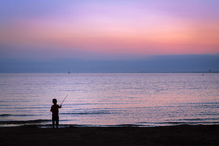 silhouette of child fishing on seashore thumbnail