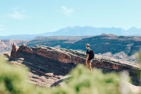 man walking on rocky pathway overlooking rocky mountains during daytime thumbnail