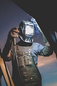 person wearing black leather overalls and black welding helmet thumbnail