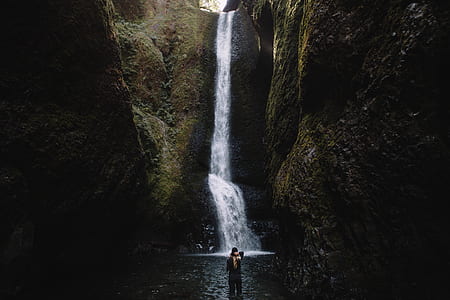 person standing near waterfalls thumbnail