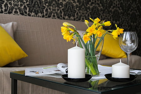 yellow daffodils centerpiece and two white pillar candles closeup photography thumbnail