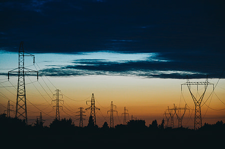 silhouette photography of transmission post under cloudy sky thumbnail