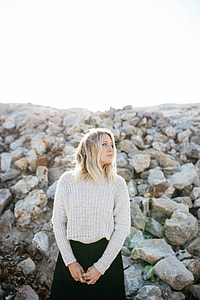 woman wearing gray knitted sweater and black skirt in front of rocks during daytime thumbnail