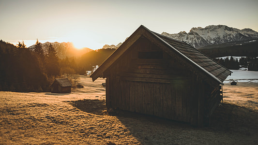 brown wooden house near body of water and trees during golden hour thumbnail