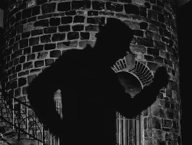 shadow of person wearing hat cast on brick wall thumbnail