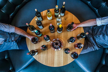 two men sitting in front of table with liquor bottles thumbnail