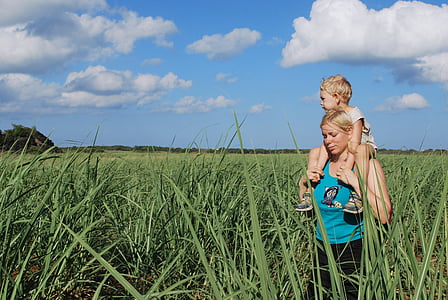 mother carrying her child while standing on grass field thumbnail
