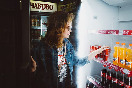 woman wearing blue denim button-up jacket holding Coca Cola tin can thumbnail