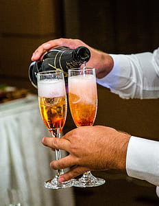 man holding bottle pouring two champagne glasses thumbnail