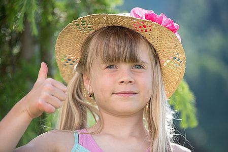 toddler's wearing brown and pink sunny hat and pink and teal top showing right thumb thumbnail