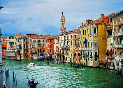 person taking photo of yellow concrete building with body of water during daytime thumbnail