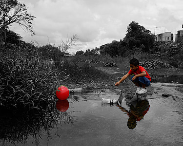 selective photography of boy sitting beside body of water thumbnail