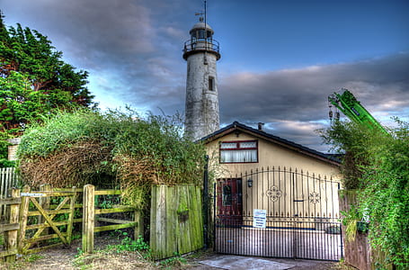 beige house near lighthouse and green trees thumbnail
