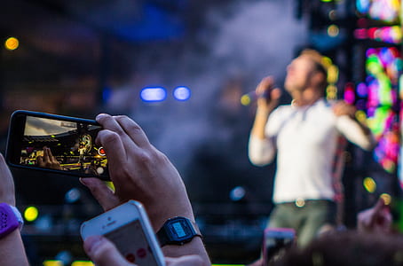 person taking video on person singing on stage selective focus photography thumbnail