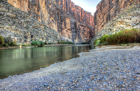 photo of body of water near brown rock mountain thumbnail