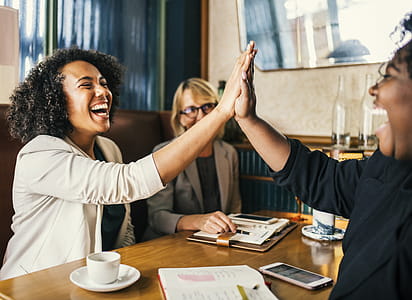 Laughing Women Sitting in Front of Table Doing High Five Clap thumbnail