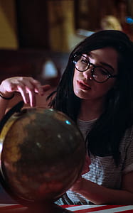 woman with eyeglasses looking at the desk globe thumbnail