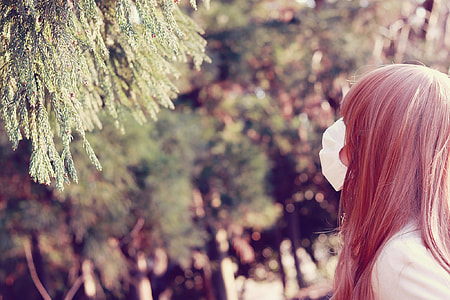 woman wearing white face mask and facing near green leaf tree thumbnail