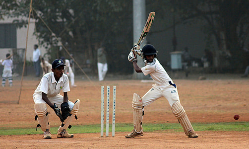 cricket batter in batting stance near catcher on playing ground during daytime thumbnail