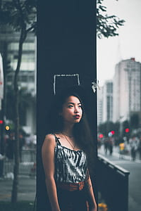 woman wearing black sun hat and grey spaghetti strap top standing near post thumbnail