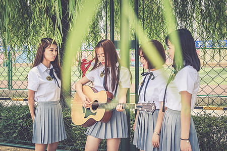 Four Woman Singing and Playing Guitar Near Cyclone Fence thumbnail