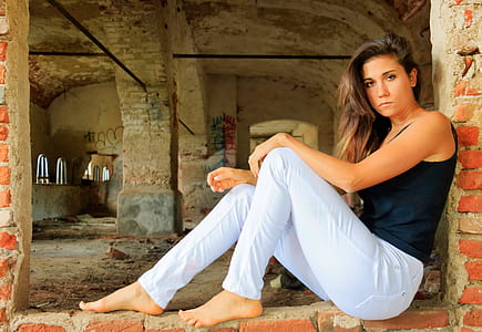 woman wearing black tank top leaning on brick wall thumbnail