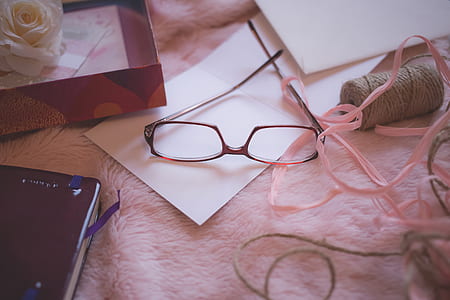 Eyeglasses Beside Pink Yarn on Pink Bed Blanket thumbnail