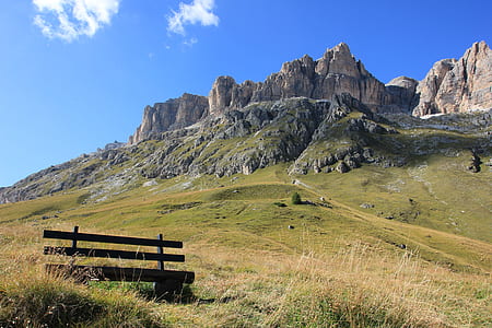 brown wooden bench near brown mountain under blue and white sky during daytime thumbnail
