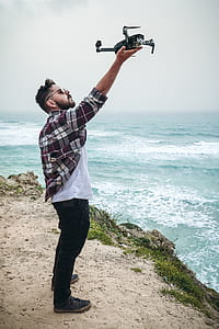man on a cliff holding drone thumbnail