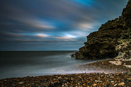 black rock formation over body of water during twilight thumbnail