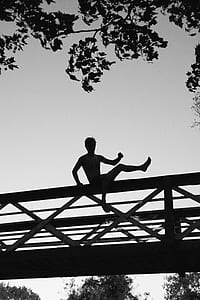 silhouette of person sitting on bridge under white clouds thumbnail