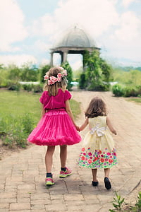 two girls walking through gray gazebo during daytime thumbnail