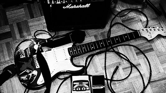 grayscale photography of electric guitar with amplifier on floor thumbnail